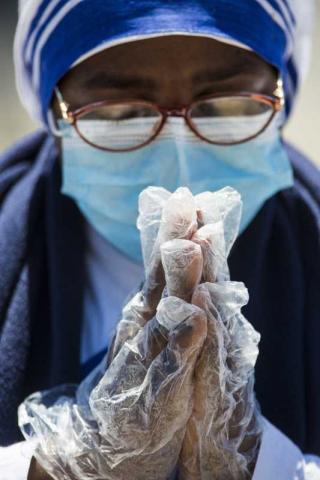 9. Pablo Esparza/Heraldo de México Città del Vaticano, 27 aprile, 2020. Una suora della comunità di Madre Teresa prega con mascherina e guanti protettivi.